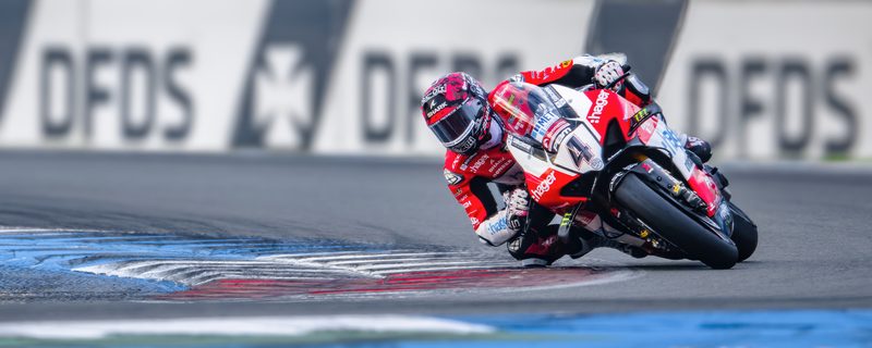 Superbike racing: rider at full lean in front of DFDS boards, Assen 2025