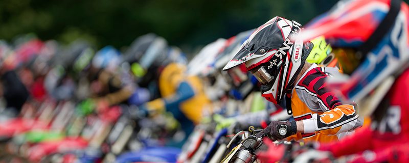 Motocross start line: riders lean over their bikes before the gate drops, Wakes Colne